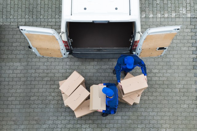 Delivery people wearing blue stacking cardboard boxes